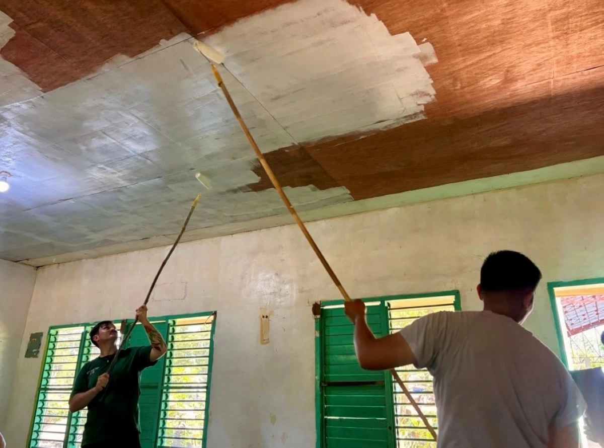 US service members team up with their Philippine counterparts in painting the ceiling of an elementary school as part of Brigada Eskwela.