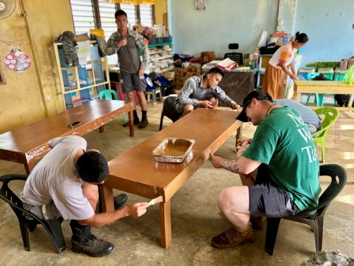 US and Philippine service members paint tables at an elementary school in Rizal, Palawan, as part of Brigada Eskwela, a nationwide effort to prepare schools for the new academic year.