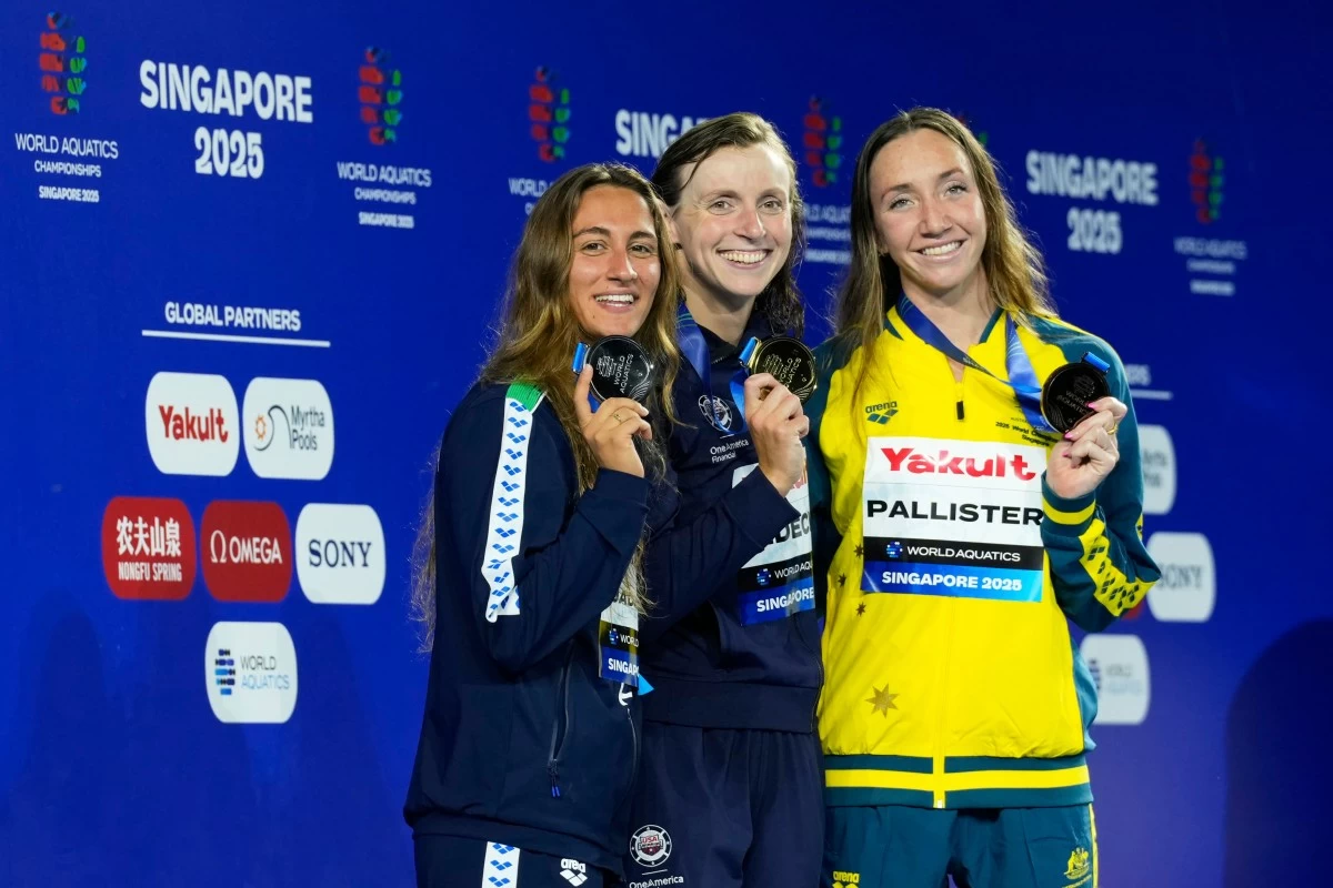 Gold medalist Katie Ledecky of the United States, center, flanked by silver medalist Simona Quadarella of Italy, left, and bronze medalist Lani Pallister of Australia pose on the podium after the women's 1500m freestyle final at the World Aquatics Championships in Singapore, Tuesday, July 29, 2025. (AP Photo/Vincent Thian)