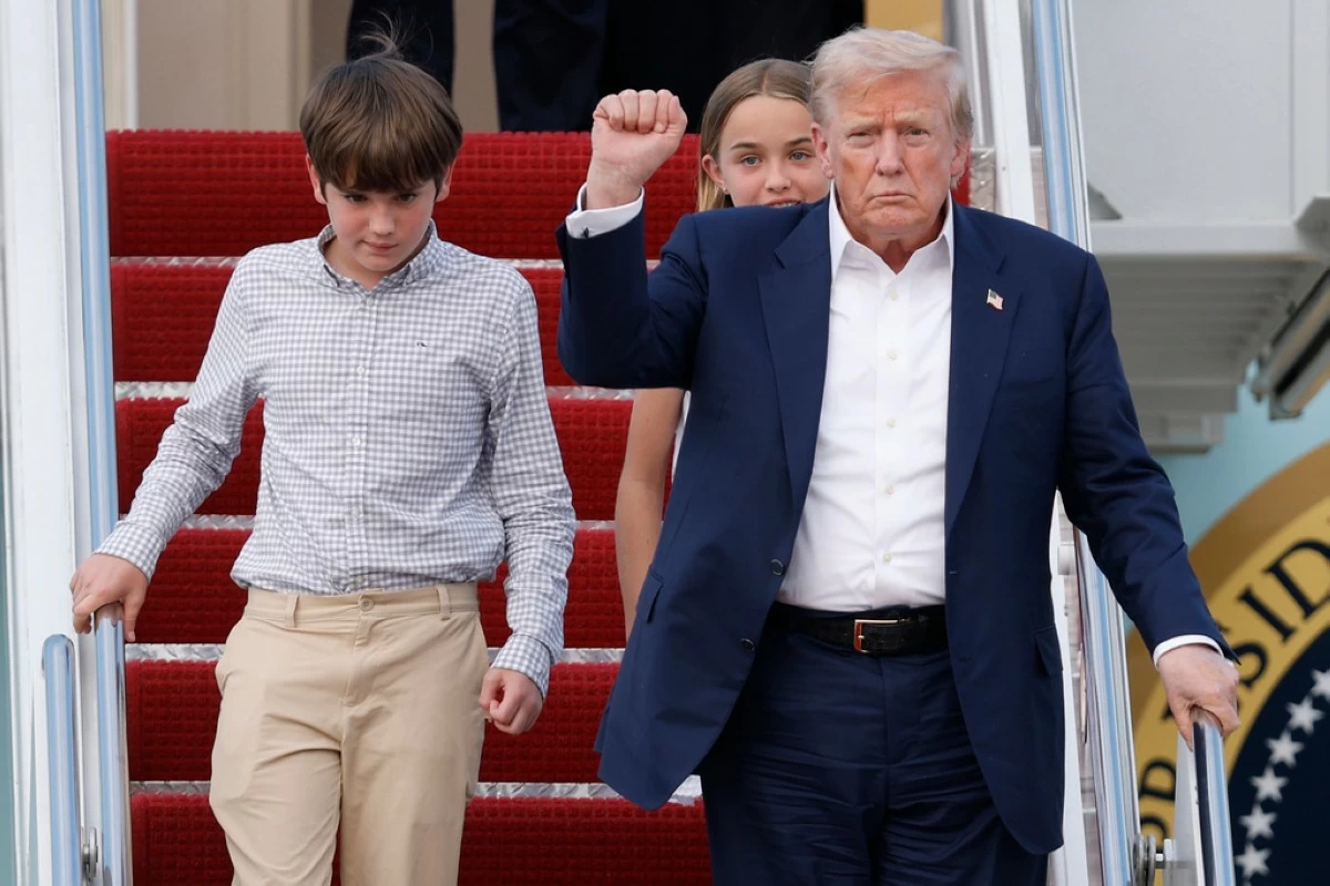 President Donald Trump, front right, gestures as he walks down the stairs of Air Force One with his grandchildren, Spencer, left, and Chloe, back center, upon his arrival at Joint Base Andrews, Md., Tuesday, July 29, 2025. (AP Photo/Luis M. Alvarez)
