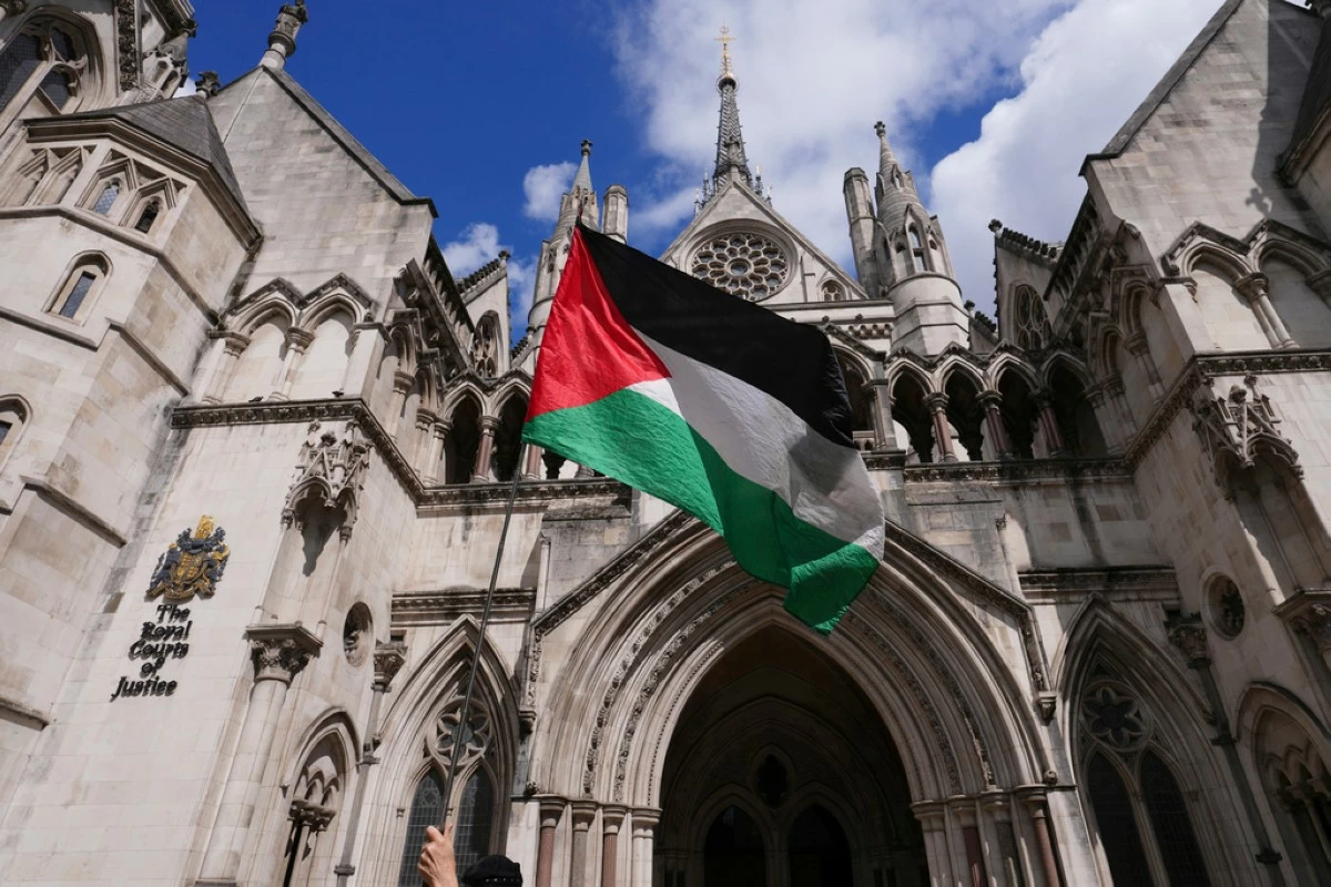 A demonstrator waves a flag outside the High Court in London where a full hearing on an application for a judicial review by Palestine Action against its impending proscription is being heard, Monday, July 21, 2025. (AP Photo/Kirsty Wigglesworth)