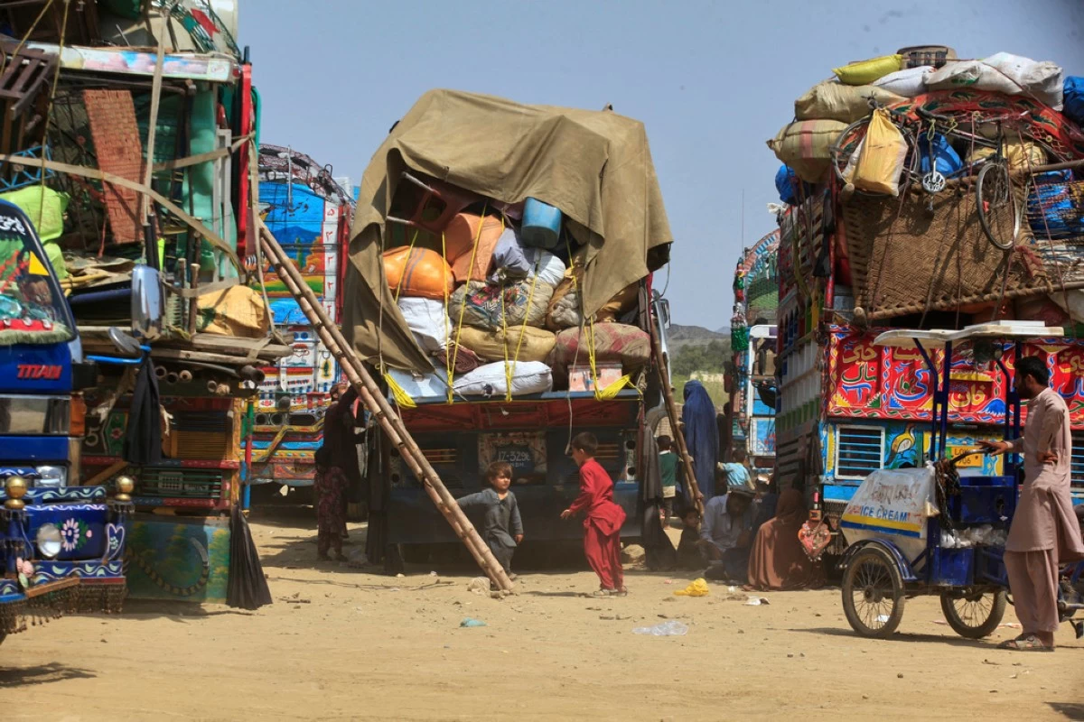 FILE - Afghan refugee children play next to trucks loaded with their family's belongings as they wait to return Afghanistan along a highway in Landi Kotal, Pakistan, April 9, 2025. (AP Photo/Muhammad Sajjad, File)