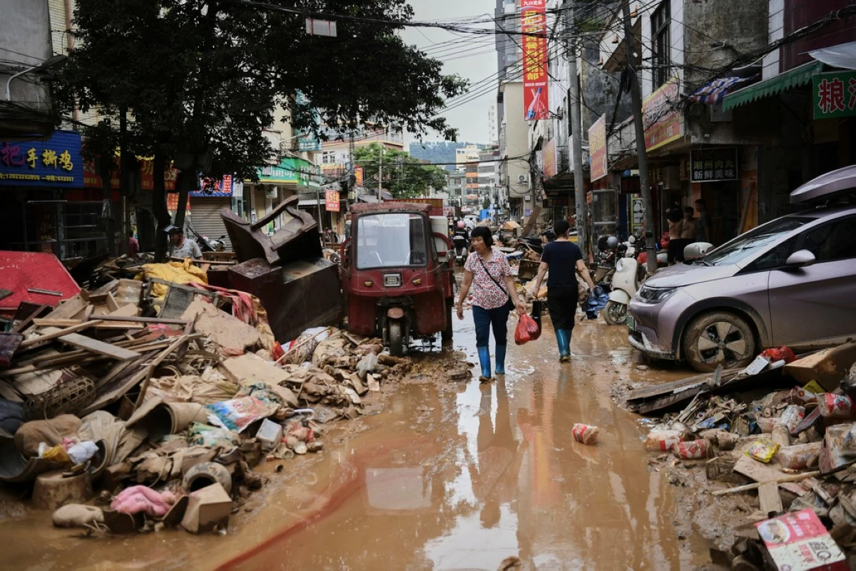FILE -In this photo released by Xinhua News Agency, residents wade through debris along a flood-hit street after waters from a river overwhelmed towns following days of heavy rain, in Huaiji County, south China's Guangdong Province on June 19, 2025. (Deng Hua/Xinhua via AP, File)