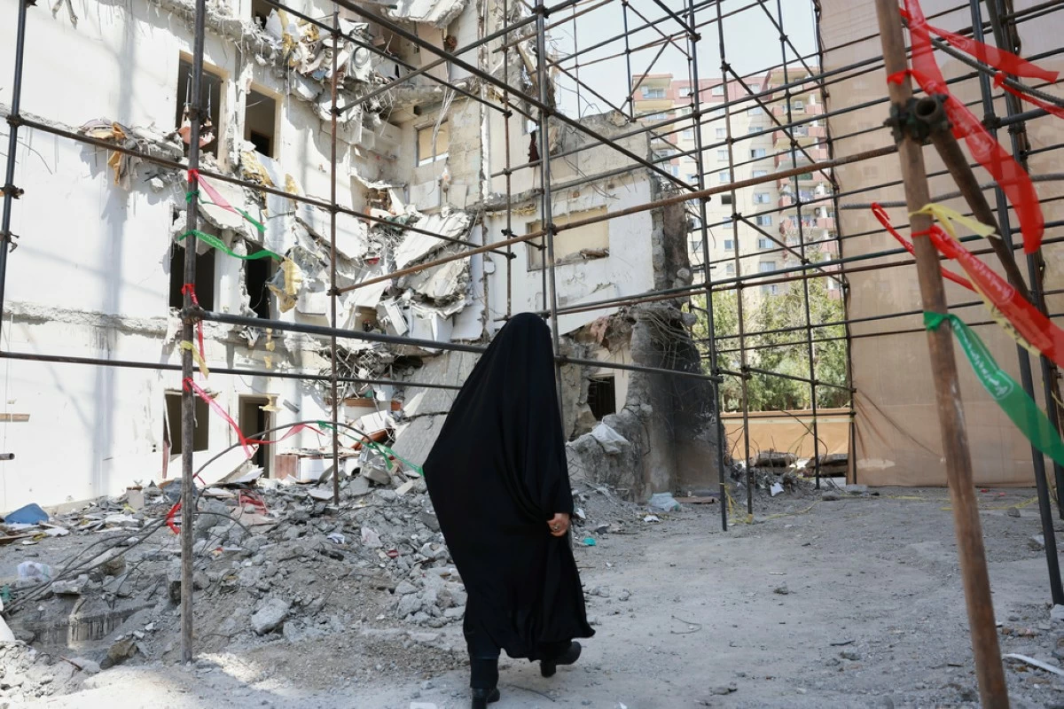 FILE -A woman walks past a building damaged in a deadly June 13 Israeli airstrike at a residential compound in Tehran, Iran, on July 19, 2025. (AP Photo, File)