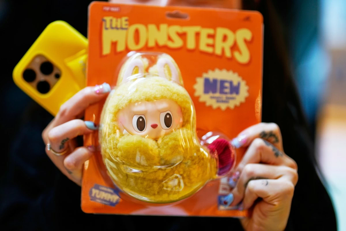 FILE - A customer shows a new Labubu doll to media during the opening of Germany's first shop for Labubu plush dolls in Berlin,  July 25, 2025. (AP Photo/Markus Schreiber, File)