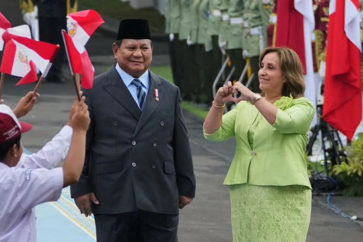 Peruvian President Dina Boluarte, right, gives a love symbol at children waving Indonesian and Peruvian flags as his Indonesian counterpart Prabowo Subianto looks on during a welcoming ceremony prior to their meeting at Merdeka Palace in Jakarta, Indonesia, Monday, Aug. 11, 2025. (AP Photo/Achmad Ibrahim)