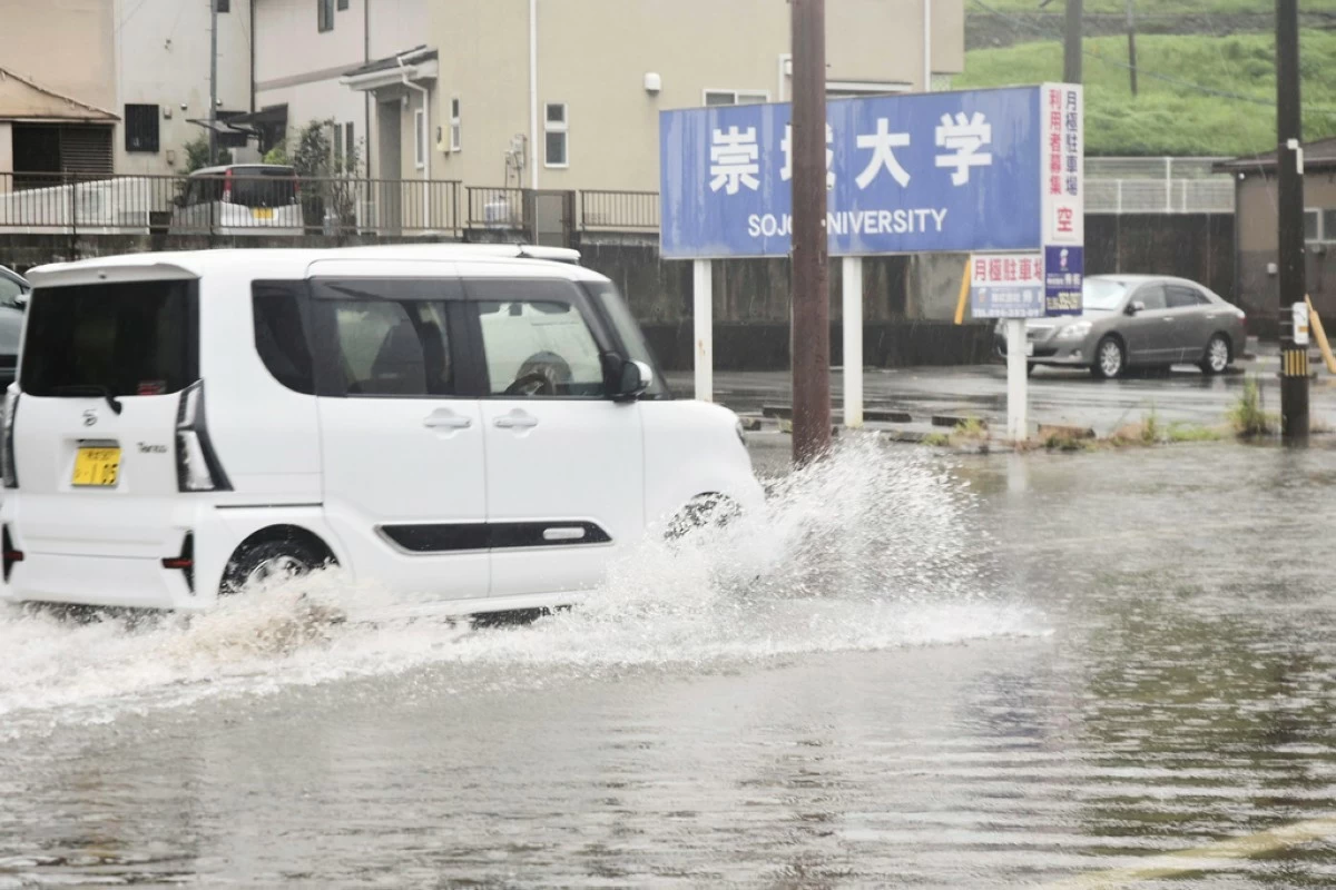 A vehicle advances through a flooded road in Kumamoto, southern Japan Monday, Aug. 11, 2025. (Kyodo News via AP)