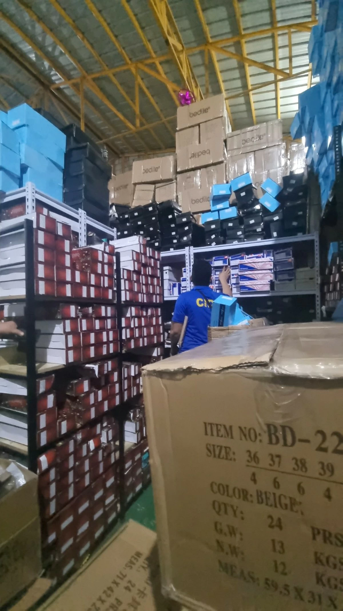 A CIDG operative checks the alleged counterfeit footwear products  following a raid in a Pasa City warehouse. (photo: CIDG)