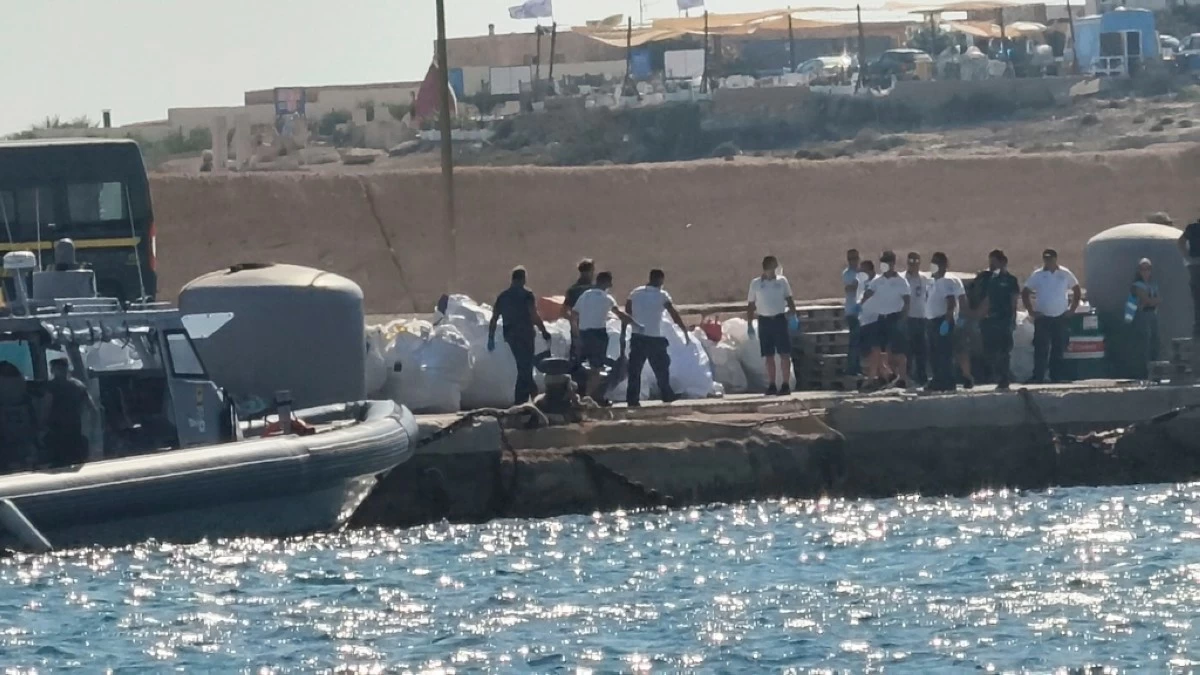 Italian Coast Guards officers carry a body bag on the dock of Lampedusa harbor Wednesday, Aug. 13, 2025, after a boat carrying nearly 100 migrants capsized off the Italian island, killing several people and leaving another dozen missing. (AP Photo/Elio Deisderio)