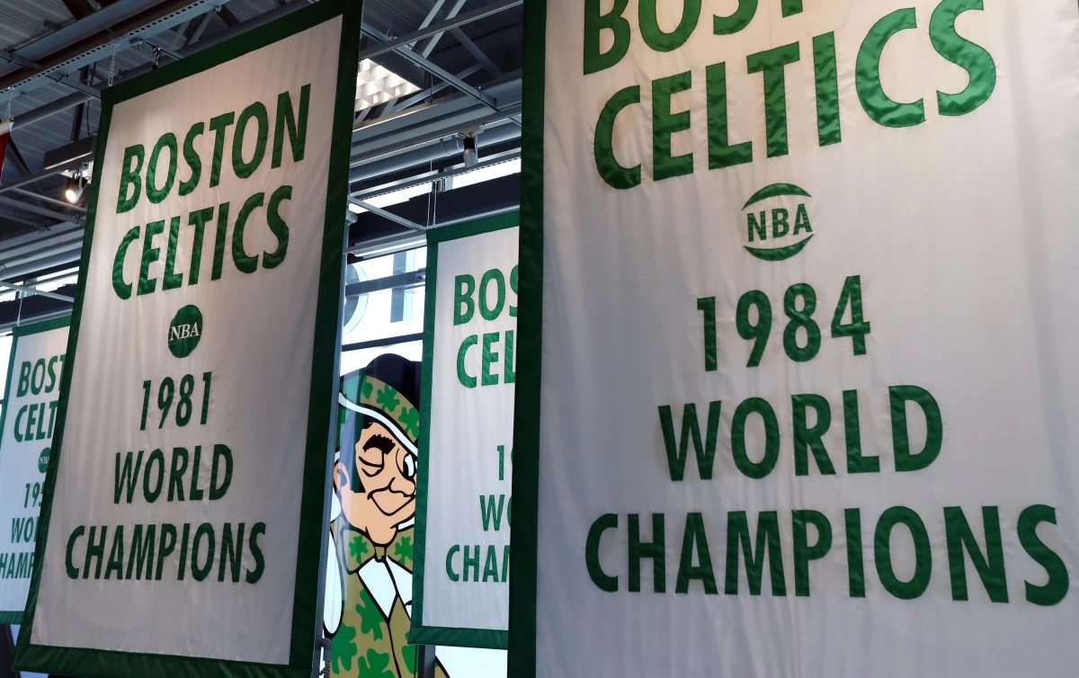 FILE - Lucky the Leprechaun, the Boston Celtics team logo, peers out from in between Celtics championship banners hanging in their new basketball team practice facility, Tuesday, June 19, 2018, in Boston. (AP Photo/Elise Amendola, File)