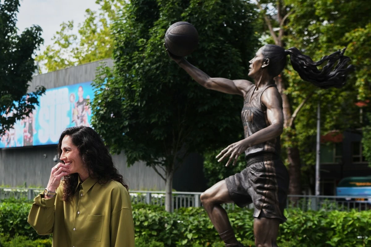 Former Seattle Storm WNBA basketball point guard Sue Bird stands near her statue after its unveiling outside Climate Pledge Arena, Sunday, Aug. 17, 2025, in Seattle. (AP Photo/Lindsey Wasson)