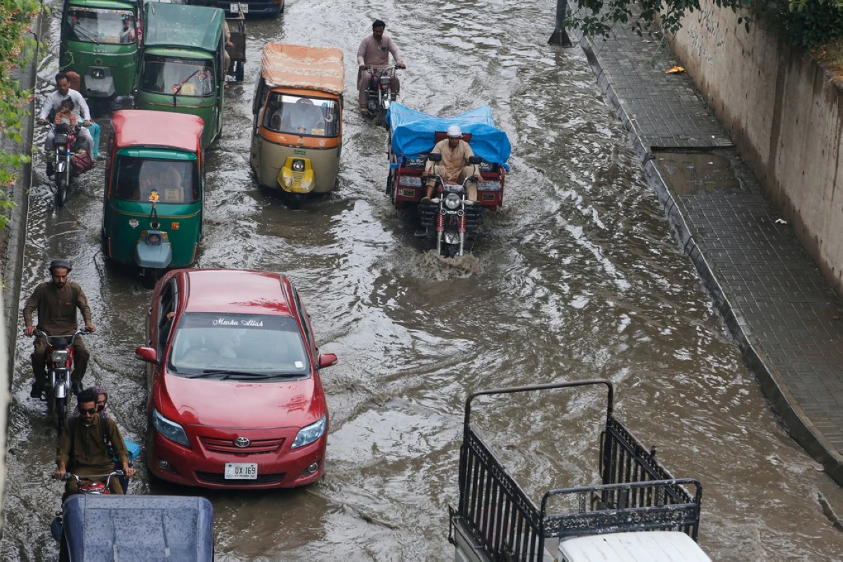 Vehicles and motorcyclists drive through a flooded road after heavy rainfall in Peshawar, Pakistan, Monday, Aug. 18, 2025. (AP Photo/Muhammad Sajjad)