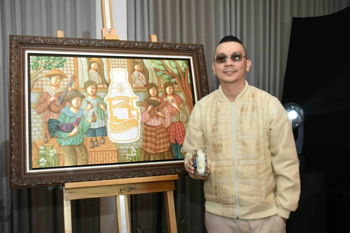 Artist Francis Nacion posing with his artwork and holding a beer with the limited-edition design