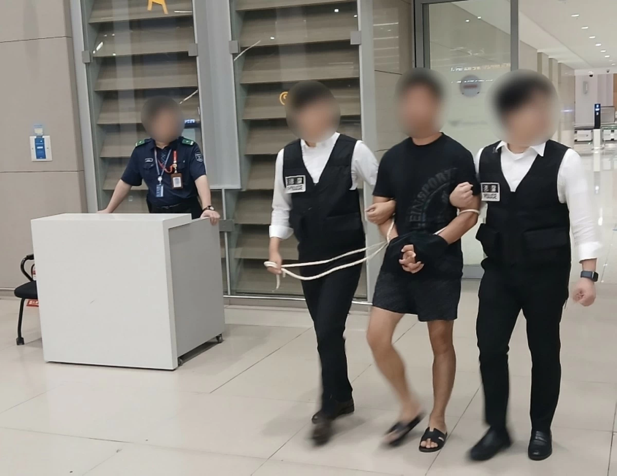 The leader of a hacking organization (center) is escorted by the police as he arrives at Incheon International Airport on Aug. 22 (Korea's Ministry of Justice)