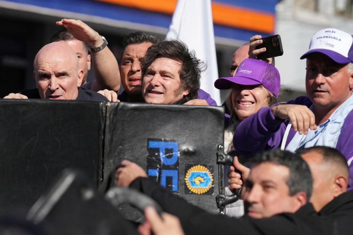 Police shield Argentine President Javier Milei and his sister, Secretary General of the Presidency, Karina Milei, from objects thrown at them by protesters amid a campaign rally ahead of legislative provincial elections in Lomas de Zamora, Argentina, Wednesday, Aug. 27, 2025. (AP Photo/Natacha Pisarenko)