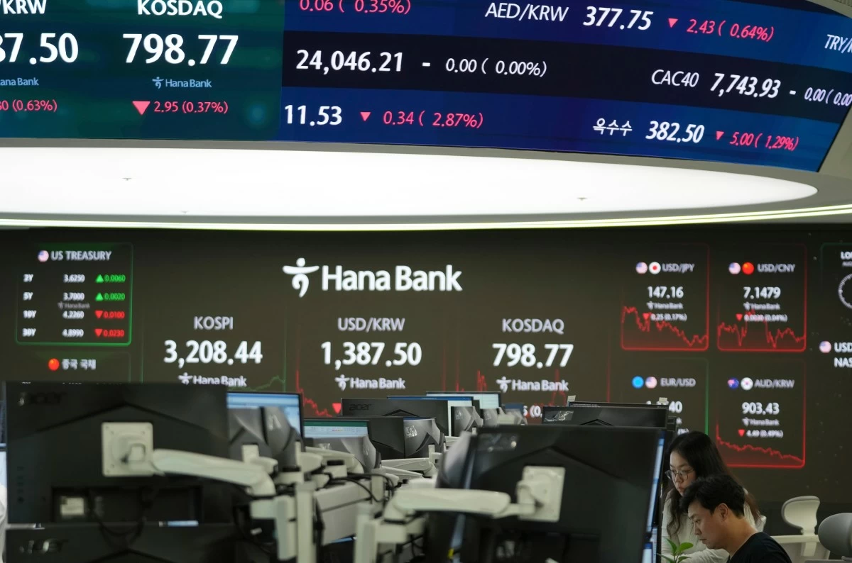 Dealers talk near the screens showing the Korea Composite Stock Price Index (KOSPI) and the foreign exchange rate between U.S. dollar and South Korean won and the Korean Securities Dealers Automated Quotations (KOSDAQ) at a dealing room of Hana Bank in Seoul, South Korea, Thursday, Aug. 28, 2025. (AP Photo/Lee Jin-man)

