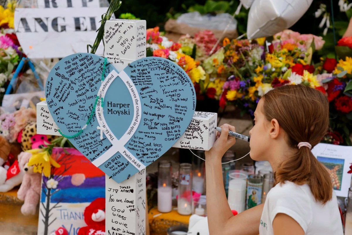 A child writes a message as people visit a make-shift memorial at Annunciation Catholic Church after the Wednesday's shooting at the school, Friday, Aug. 29, 2025, in Minneapolis. (AP Photo/Bruce Kluckhohn)