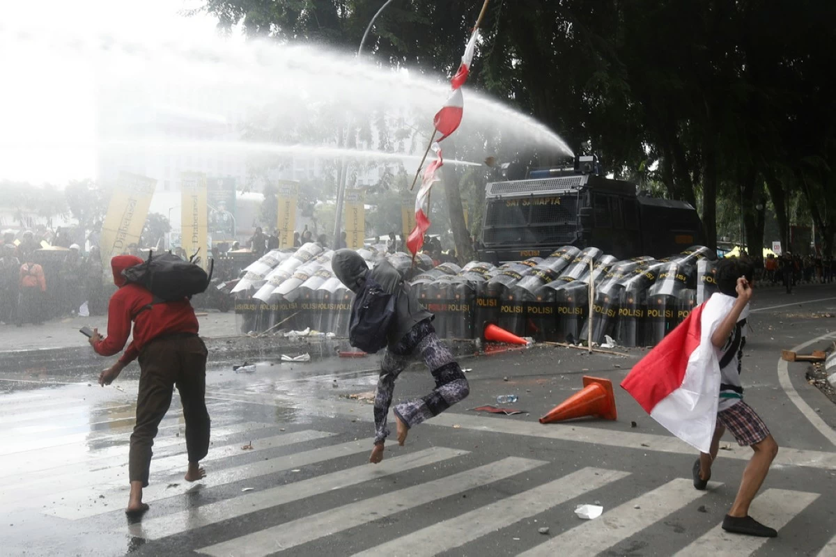 People throw rocks at the police during a protest following the death of a delivery rider in clashes between riot police and students protesting against lawmakers' allowances, in Medan, North Sumatra, Indonesia, Friday, Aug. 29, 2025. (AP Photo/Binsar Bakkara)