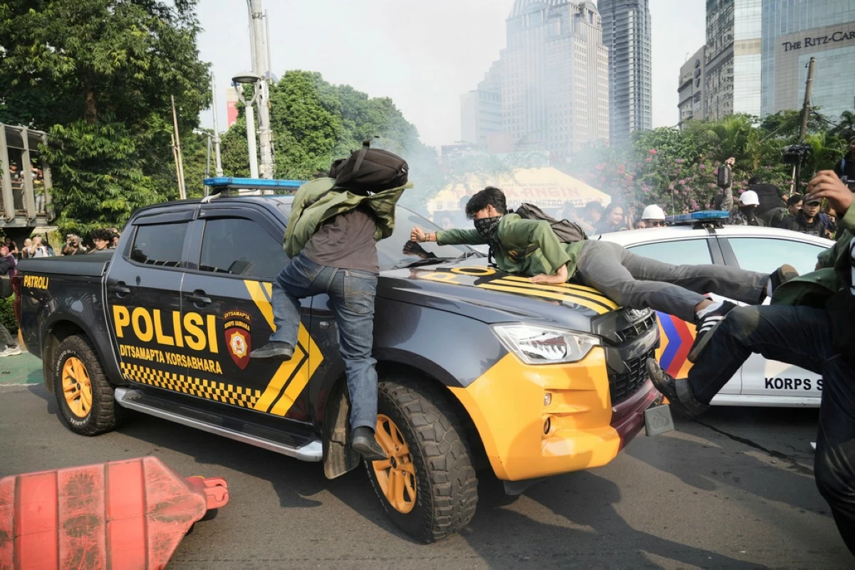 Students block a police truck during a protest following the death of a delivery rider who was run over by a police armored vehicle in a rally against lawmakers' privilege, in Jakarta, Indonesia, Friday, Aug. 29, 2025. (AP Photo/Tatan Syuflana)