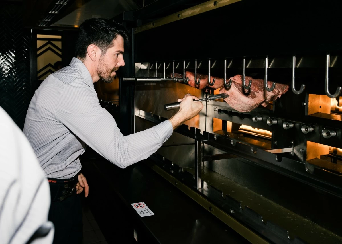 GRILL MASTER A gaucho chef tends to skewers over open flames, turning the art of churrasco into a smoky, savory ritual.
