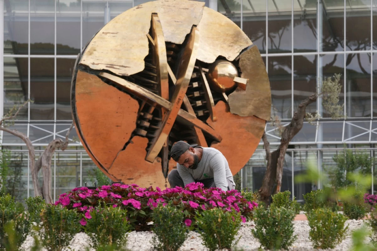 Singh Gurinder Pal, from India, tends to flowers in front of Arnaldo Pomodoro's sculpture 'The Rose of the Desert' in the plaza of the main building of the Laudato Si' Advanced Training Center inside the Vatican estate in Castel Gandolfo, near Rome, Tuesday, Sept. 2, 2025. (AP Photo/Domenico Stinellis)