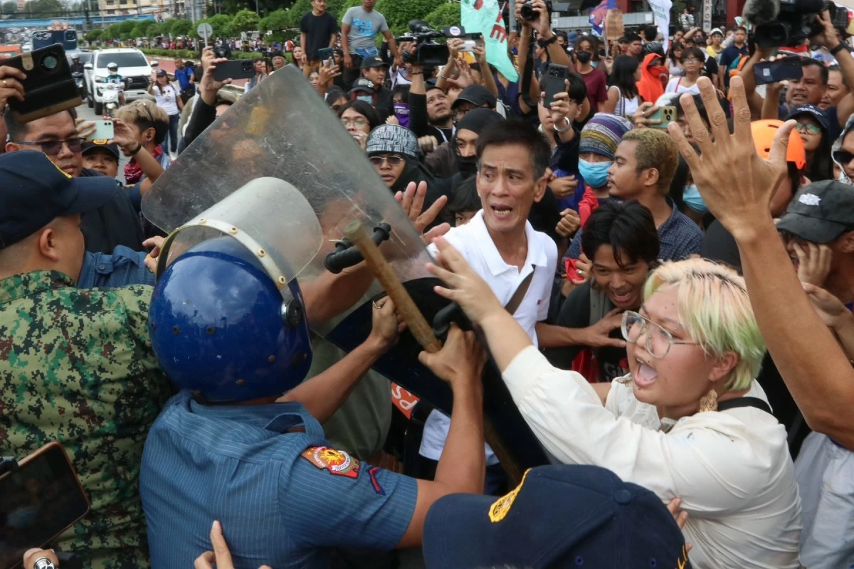 Protesters clash with members of the Quezon City Police District after throwing plastic bags with paint in a tarpaulin mimicking government project contract details which eventually hit riot police during a protest against the budget deliberation of the Department of Public Works and Highways at the House of Representatives in Quezon City on Friday, September 5, 2025. (Santi San Juan)