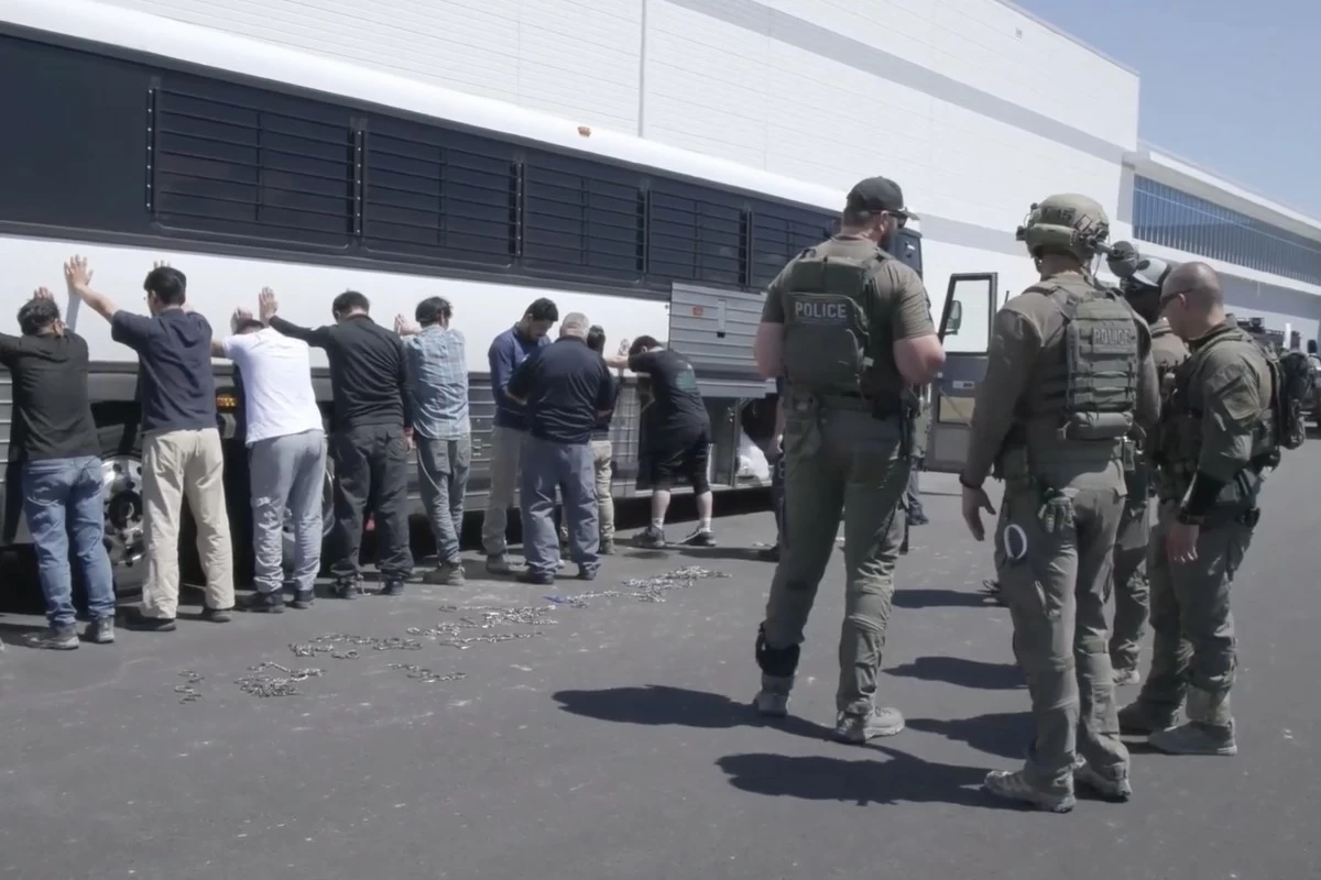 THIS image from video provided by US Immigration and Customs Enforcement via DVIDS shows manufacturing plant employees waiting to have their legs shackled at the Hyundai Motor Group’s electric vehicle plant, Thursday, Sept. 4, 2025, in Ellabell, Goergia. (US Immigration and Customs Enforcement via AP)