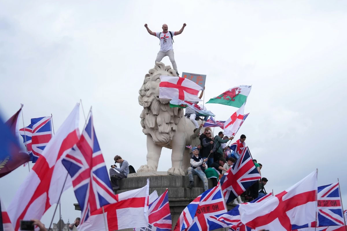 A demonstrator stands on the head of the South Bank lion that sits on the side of the Westminster Bridge, during a Tommy Robinson-led Unite the Kingdom march and rally in London, Saturday, Sept. 13, 2025. (AP Photo/Joanna Chan)