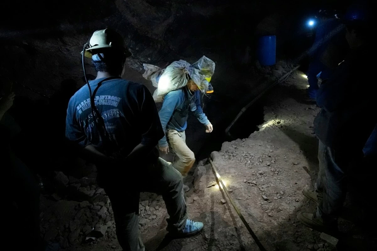 Miners carry sacks filled with mercury ore while their colleagues light the way in San Joaquin, Mexico, Tuesday, Aug. 19, 2025. (AP Photo/Fernando Llano)
