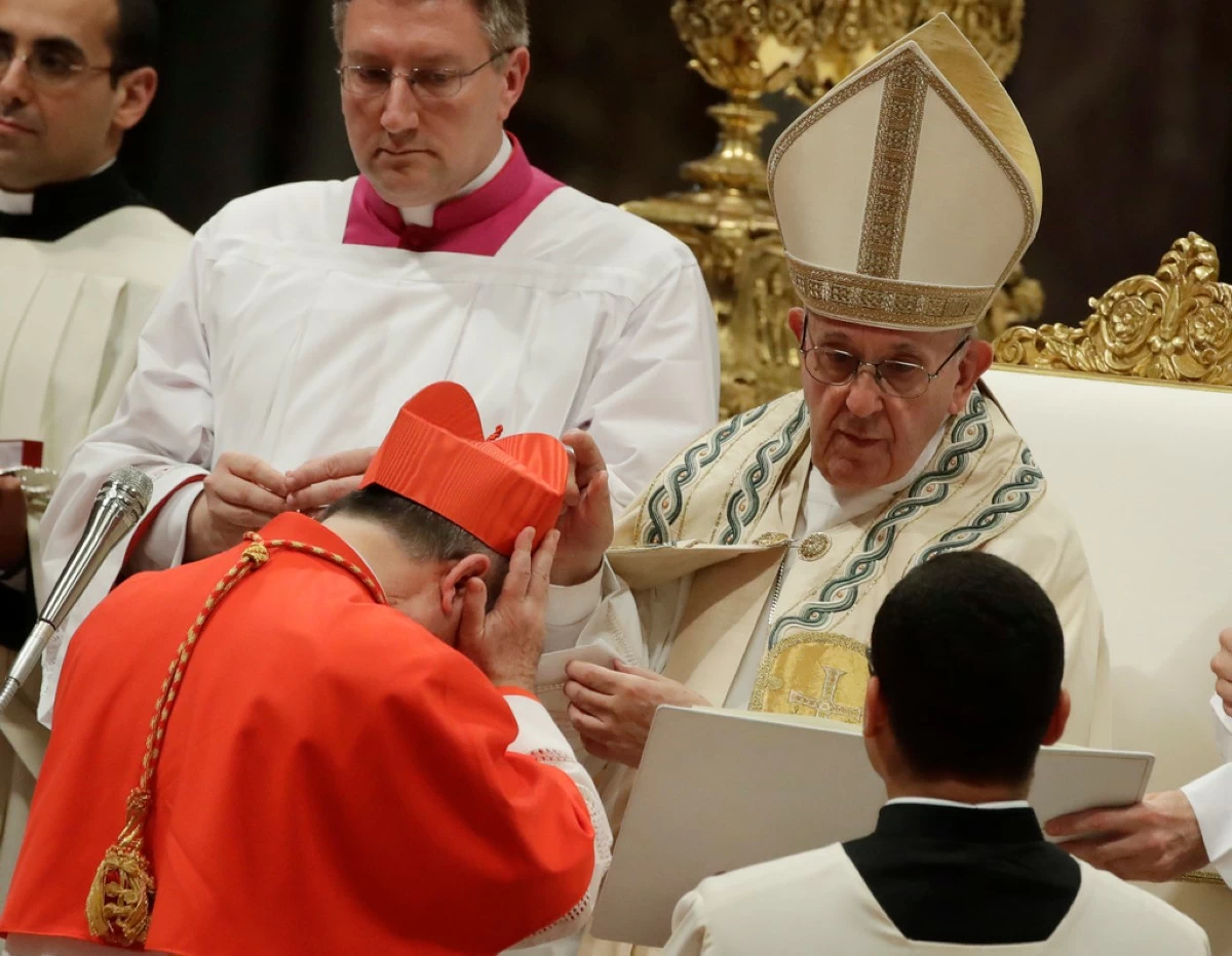 FILE - Cardinal Giovanni Angelo Becciu receives the red three-cornered biretta hat from Pope Francis during a consistory in St. Peter's Basilica at the Vatican, June 28, 2018. (AP Photo/Alessandra Tarantino, File)