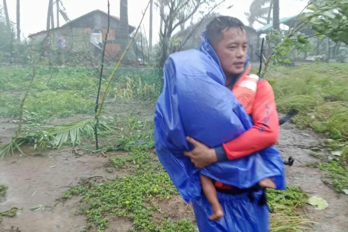 In this photo provided by the Philippine Coast Guard, a rescuer evacuates a child to safer grounds as Super Typhoon Ragasa affects Santa Ana, Cagayan province, northern Philippines, Monday, Sept. 22, 2025. (Philippine Coast Guard via AP)