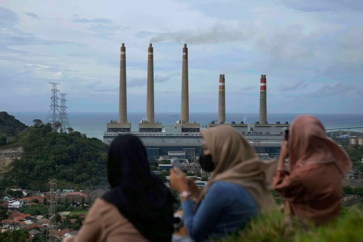 FILE - Women sit on a hill overlooking the Suralaya coal power plant in Cilegon, Indonesia, Jan. 8, 2023. (AP Photo/Dita Alangkara, File)