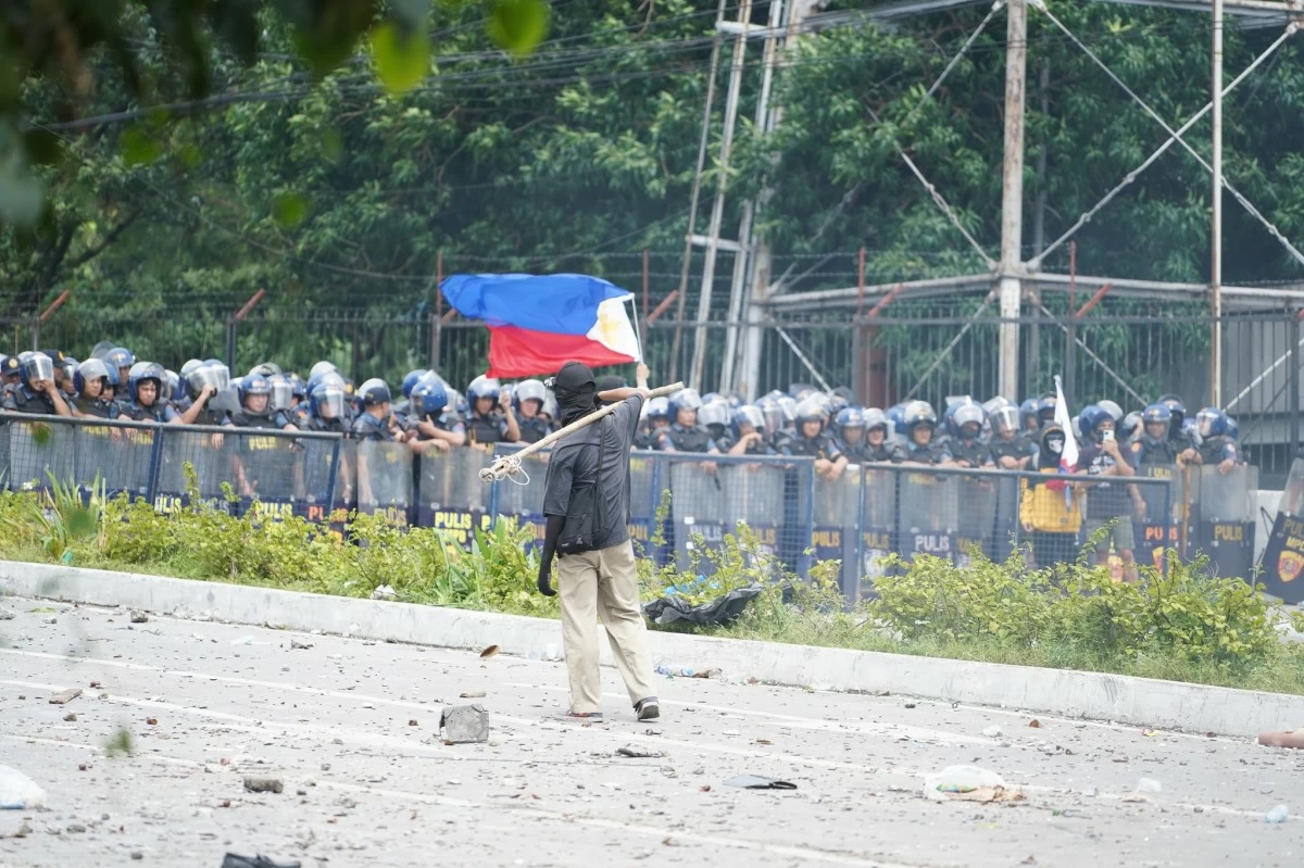 A rallyist holding a flag stands in front of a line of police on Ayala Bridge on September 21. (Photo courtesy of the Manila Public Information Office)
