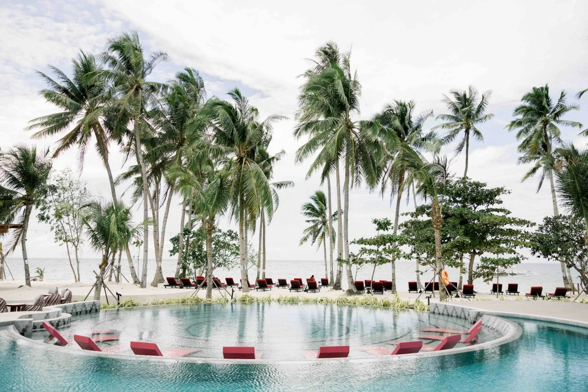 BEACHFRONT HAVEN The South Palms MGallery Panglao opens onto a shoreline framed by tropical trees and outdoor pools, offering a tranquil island setting.