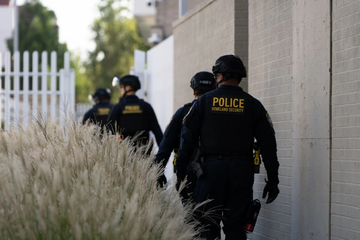 Department of Homeland Security officials walk to the gates of the U.S. Immigration and Customs Enforcement facility after inspecting an area outside on Sunday, Sept. 28, 2025, in Portland, Ore. (AP Photo/Jenny Kane)