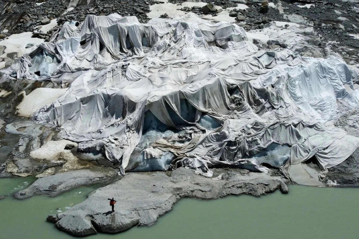 Matthias Huss, of the Federal Institute of Technology in Zurich and glacier monitoring group GLAMOS, stands at the Rhone Glacier that is partially covered with sheets near Goms, Switzerland, on June 10, 2025. (AP Photo/Matthias Schrader, File)