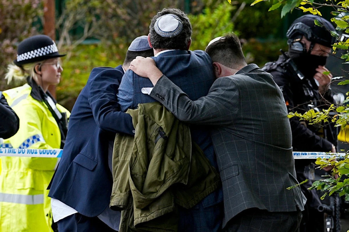 Members of the Jewish community comfort each other near to the Heaton Park Hebrew Congregation synagogue, in Crumpsall, Manchester, England, Thursday, Oct. 2, 2025 after Police reported that two people were killed and three others were seriously injured in a synagogue attack in northern England. (Peter Byrne/PA via AP)