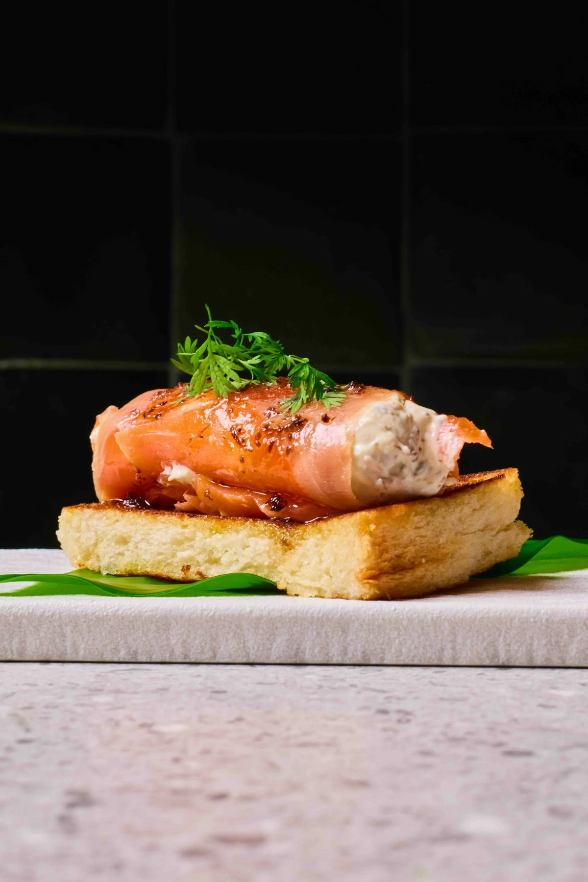 SMOKED INDULGENCE House-smoked salmon layered with truffle honey, cheese, and caviar on brioche, offering richness in every bite.