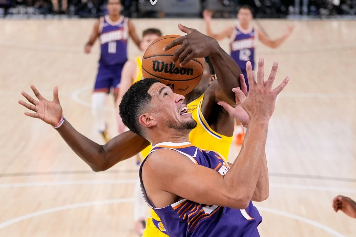 Los Angeles Lakers' Nate Williams grabs a rebound away from Phoenix Suns guard Devin Booker during the first half of an NBA preseason basketball game Friday, Oct. 3, 2025, in Palm Desert, Calif. (AP Photo/Mark J. Terrill)