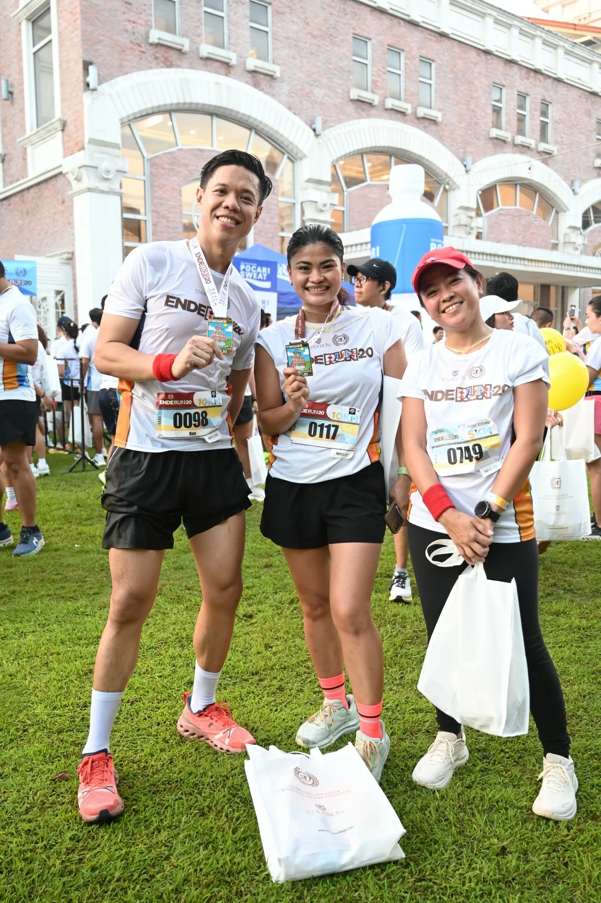 Proud runners showing off their Enderun@20 medals after crossing the finish line
