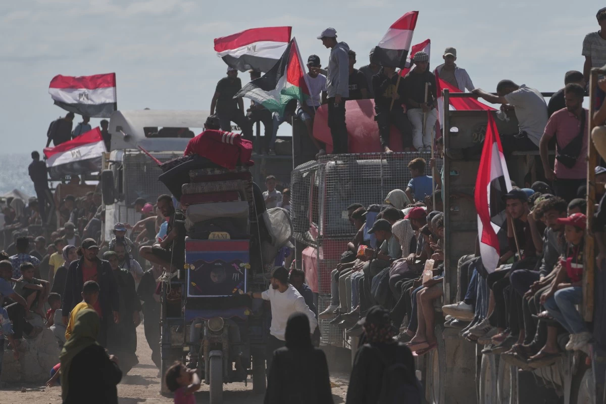 Displaced Palestinians ride on trucks loaded with belongings and wave Egyptian and Palestinian flags as they travel along the coastal road near Wadi Gaza in the central Gaza Strip, moving toward Gaza City, Saturday, Oct. 11, 2025, after Israel and Hamas agreed to a pause in their war and the release of the remaining hostages. (AP Photo/Jehad Alshrafi)