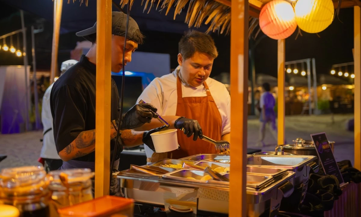 ISLAND BITES Vendors serve grilled favorites and local snacks along the beach, adding flavor and warmth to the festive Oktoberfest scene