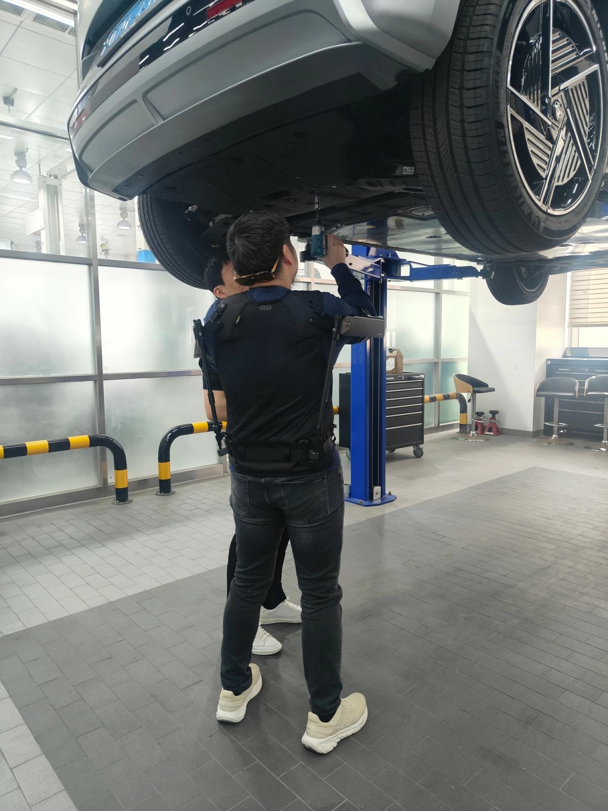A member of the media tries out workshop tasks while fitted with the X-ble Shoulder wearable robot.