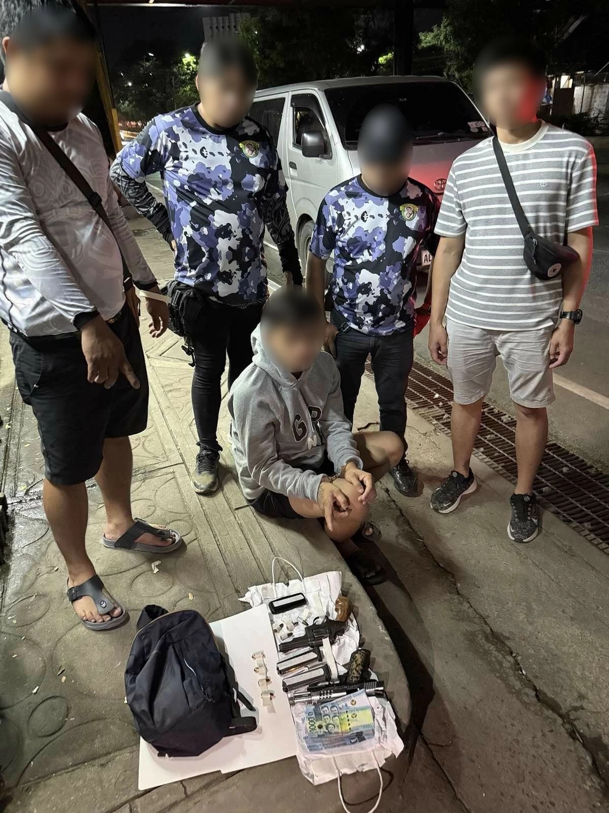 The arrested suspect (seated) and confiscated pieces of evidence (Photo from SPD) 