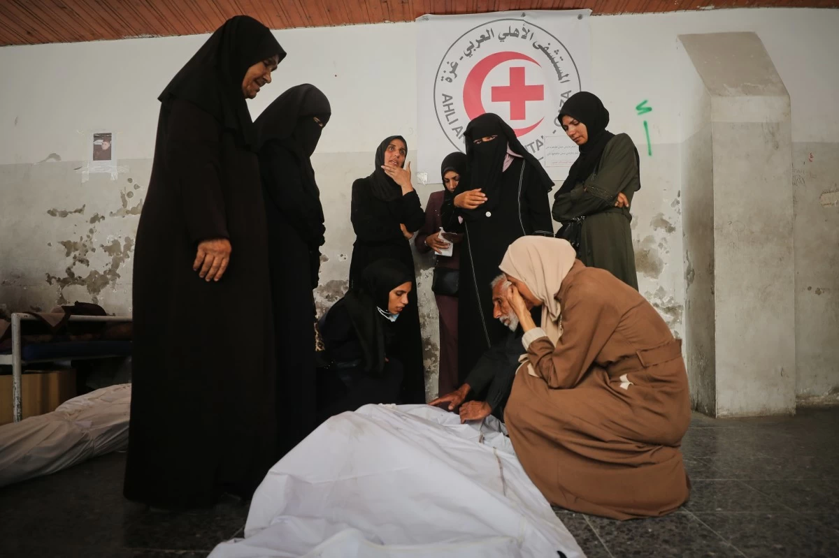 Mourners gather around the bodies of Palestinians, killed by Israeli fire after crossing the ceasefire line according to the Hamas-run Civil Defense, as they brought to Al Ahli Hospital in Gaza City, Saturday, Oct. 18, 2025. (AP Photo/Yousef Al Zanoun)