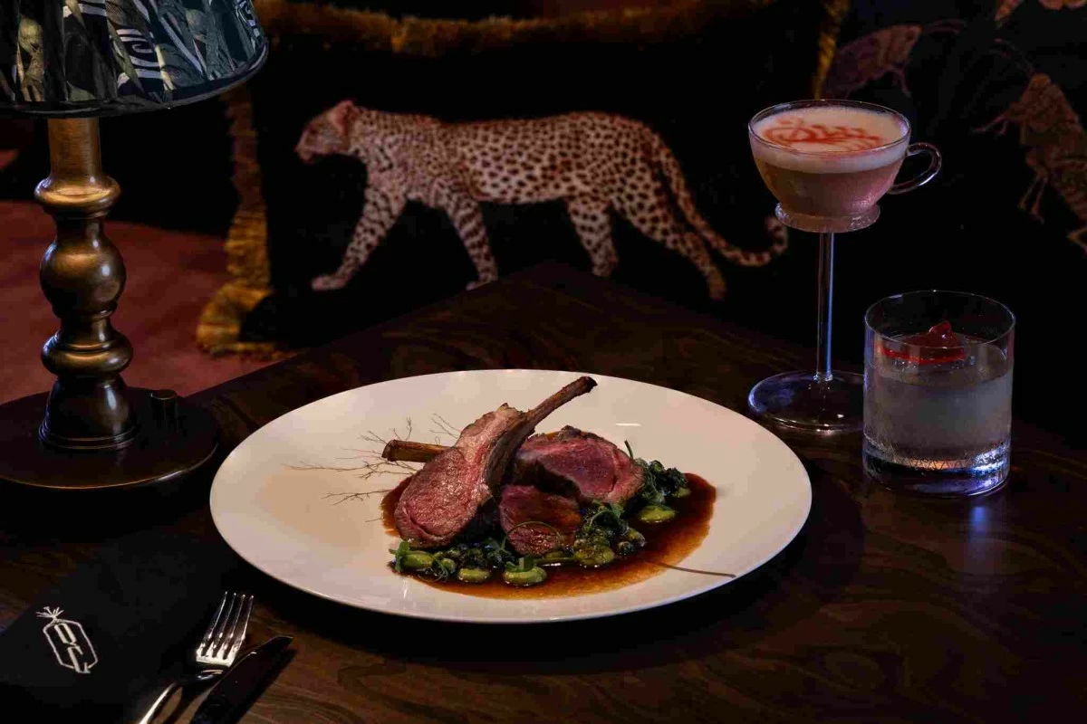 LAMB LUXE A perfectly seared lamb rack plated with snap pea purée and port wine jus at