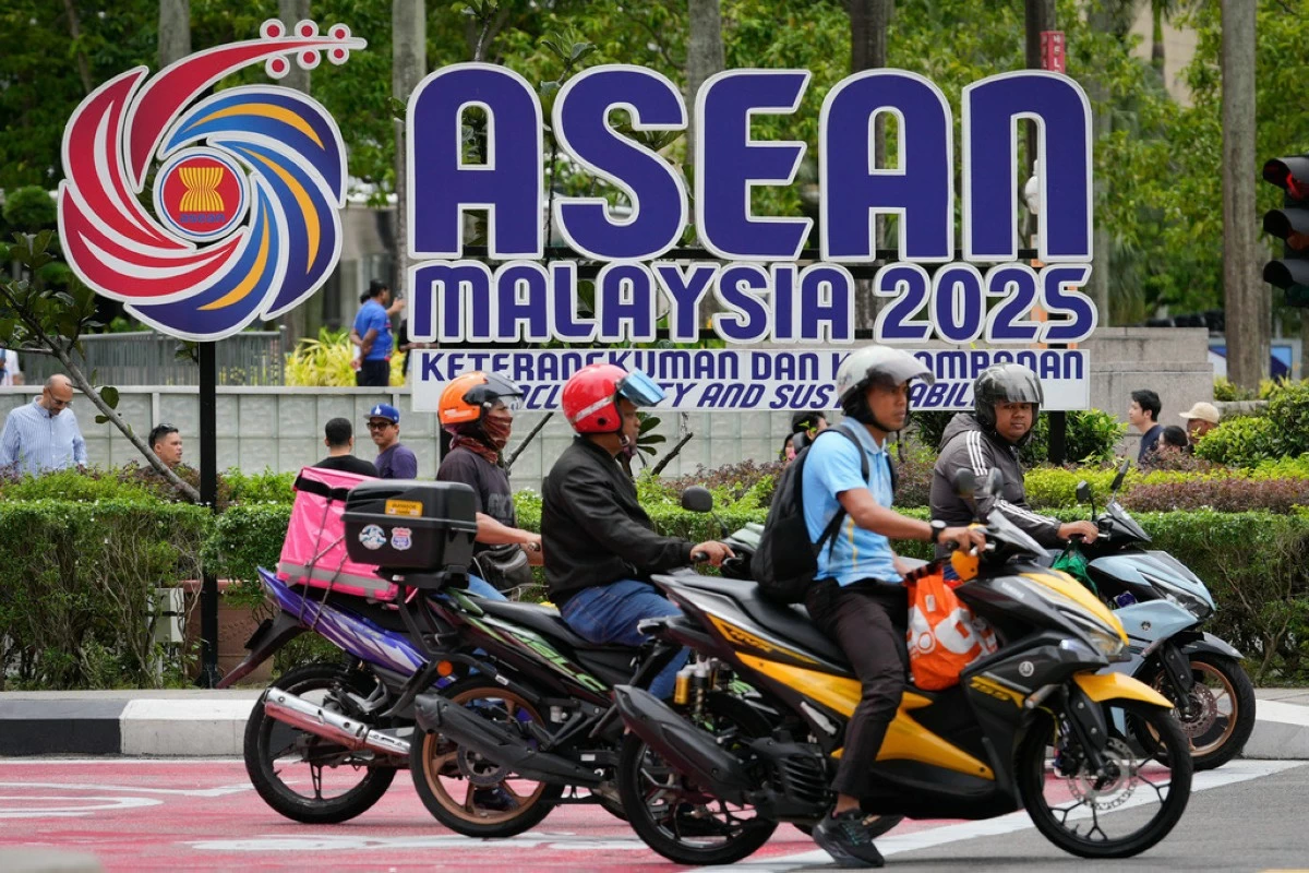 Motorists stop at a traffic light next to the logo of the Association of Southeast Asian Nations (ASEAN) in front of Malaysia's Petronas Twin Towers ahead of the 47th ASEAN Summit in Kuala Lumpur, Malaysia, Friday, Oct. 24, 2025. (AP Photo/Vincent Thian)