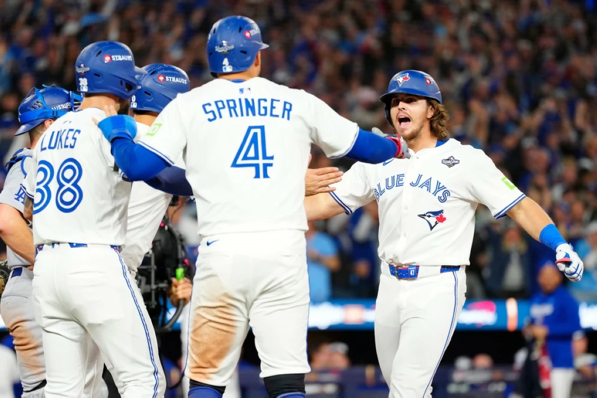 Toronto Blue Jays' Addison Barger, right, celebrates with teammates George Springer (4), Nathan Lukes, front left, and Andrés Giménez (obscured) after hitting a grand slam against the Los Angeles Dodgers during the sixth inning of Game 1 of baseball's World Series in Toronto, Friday, Oct. 24, 2025. (Frank Gunn/The Canadian Press via AP)