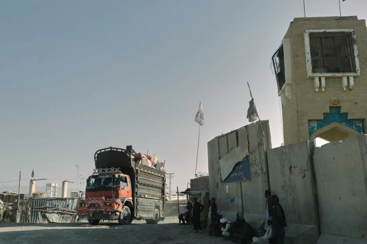 People wait near the closed gate at the Spin Boldak border crossing with Pakistan, after the border was shut for nearly two weeks following clashes between Afghan and Pakistani forces, in Kandahar province, Afghanistan, Thursday, Oct. 23, 2025. (AP Photo/Sibghatullah)