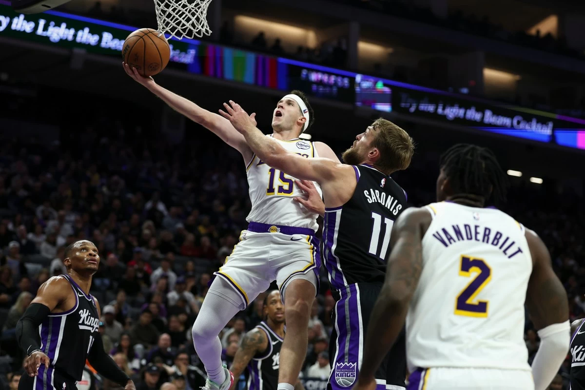 Los Angeles Lakers guard Austin Reaves, left, draws a foul on Sacramento Kings center Domantas Sabonis (11) during the first half of an NBA basketball game, Sunday, Oct. 26, 2025, in Sacramento, Calif. (AP Photo/Sara Nevis)
